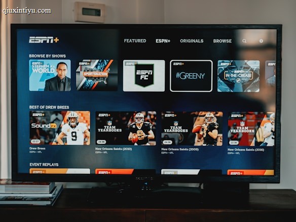 A television screen displaying the ESPN+ streaming interface with various sports-related shows and categories. The screen includes sections such as 'Browse by Shows' and 'Best of Drew Brees' with thumbnails of sports programs featuring athletes in action and analysts.